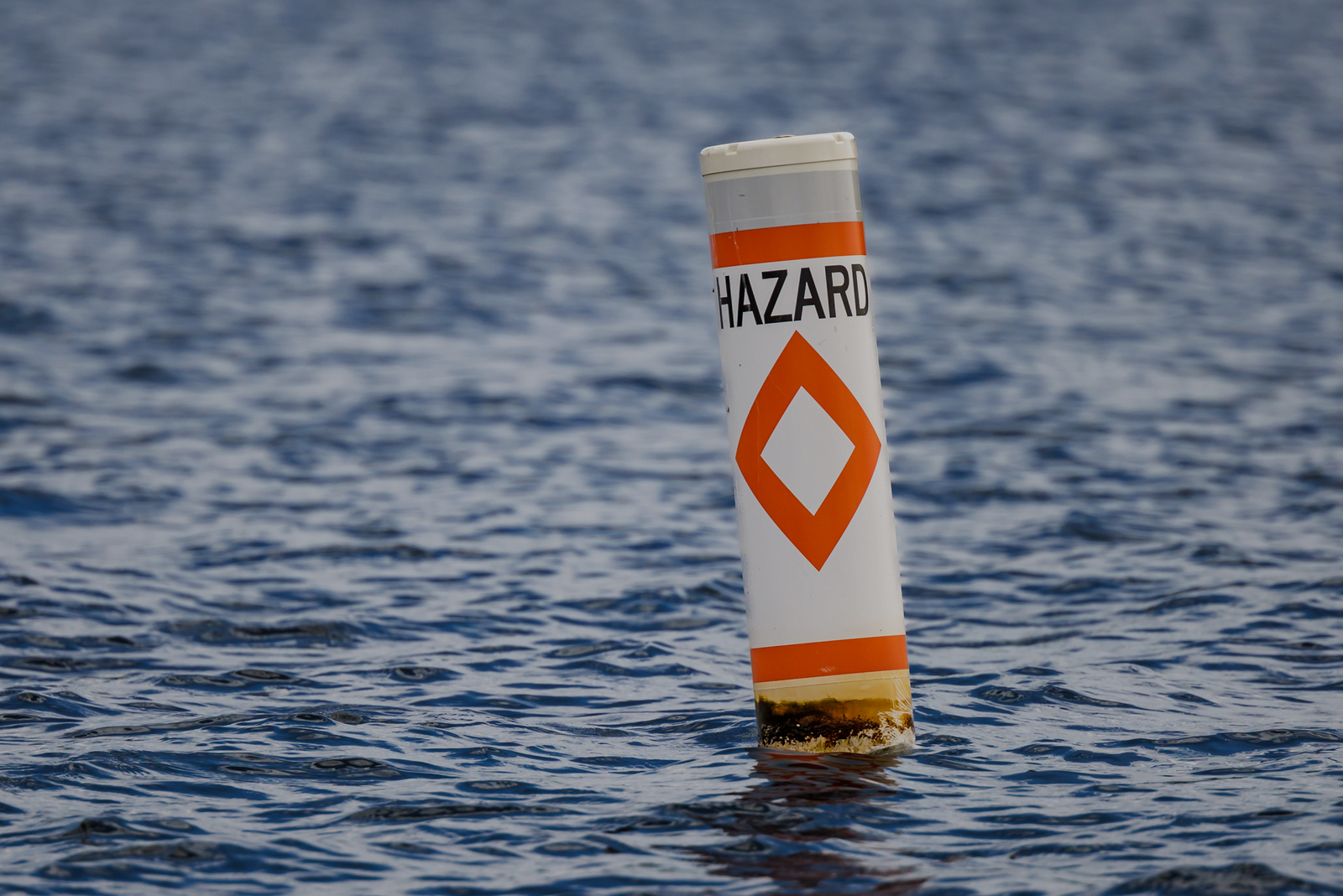 A buoy floating in the water marked with the word “hazard,” symbolizing hidden risks that can sink a charter business.