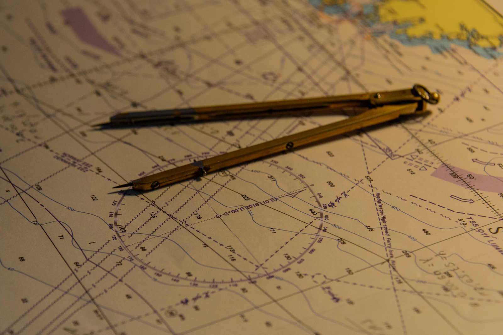 A nautical chart with a navigation divider tool placed on the map, symbolizing a complete charter route plan.