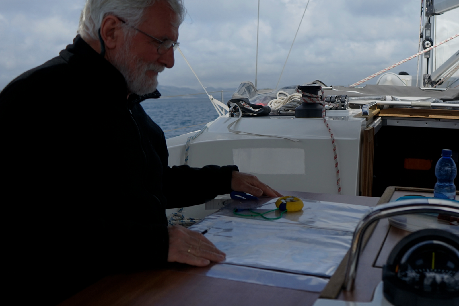 Man studying nautical charts on a sailboat.