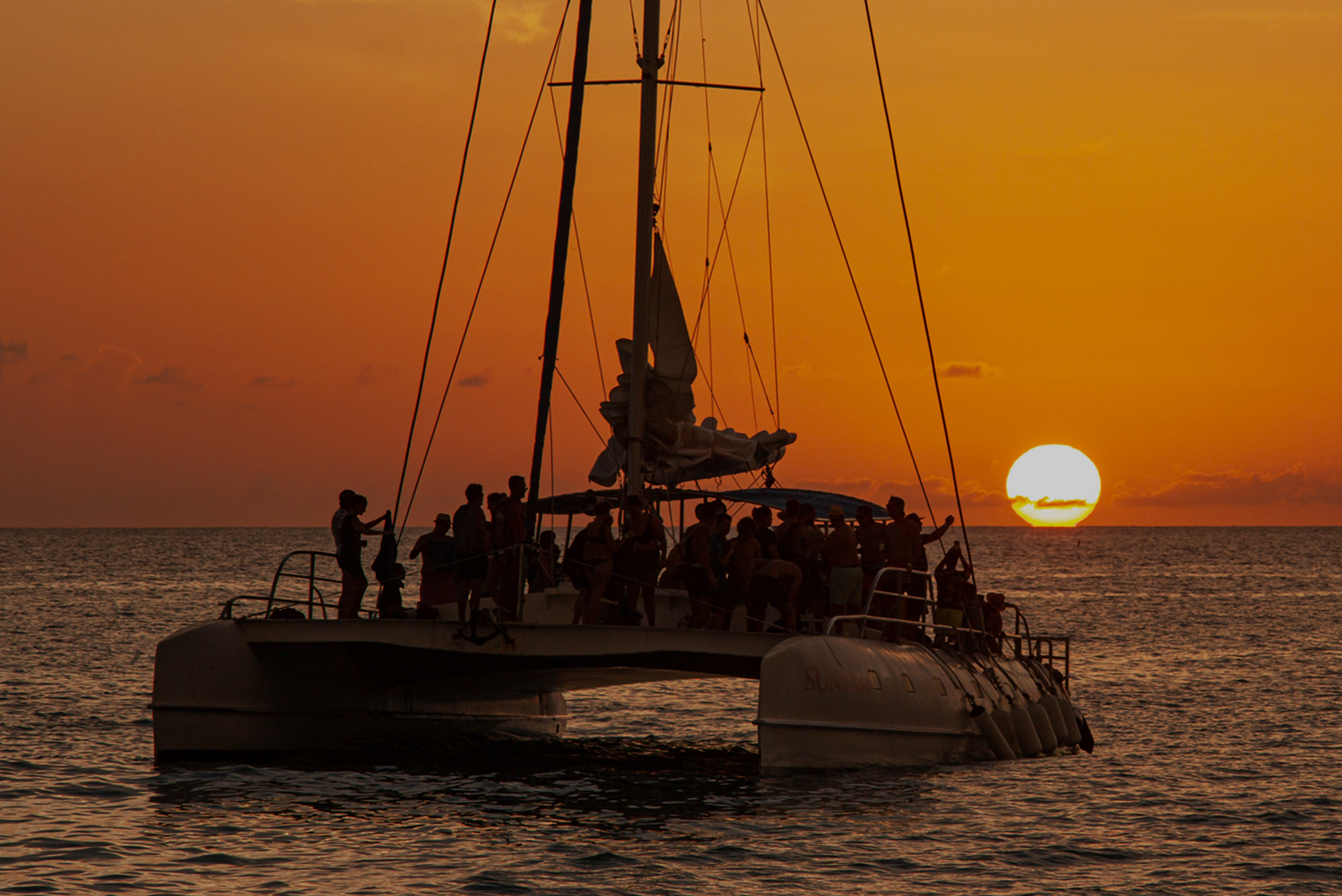 A boat filled with passengers gliding across the water at dusk, symbolizing how to find your perfect charter clients.