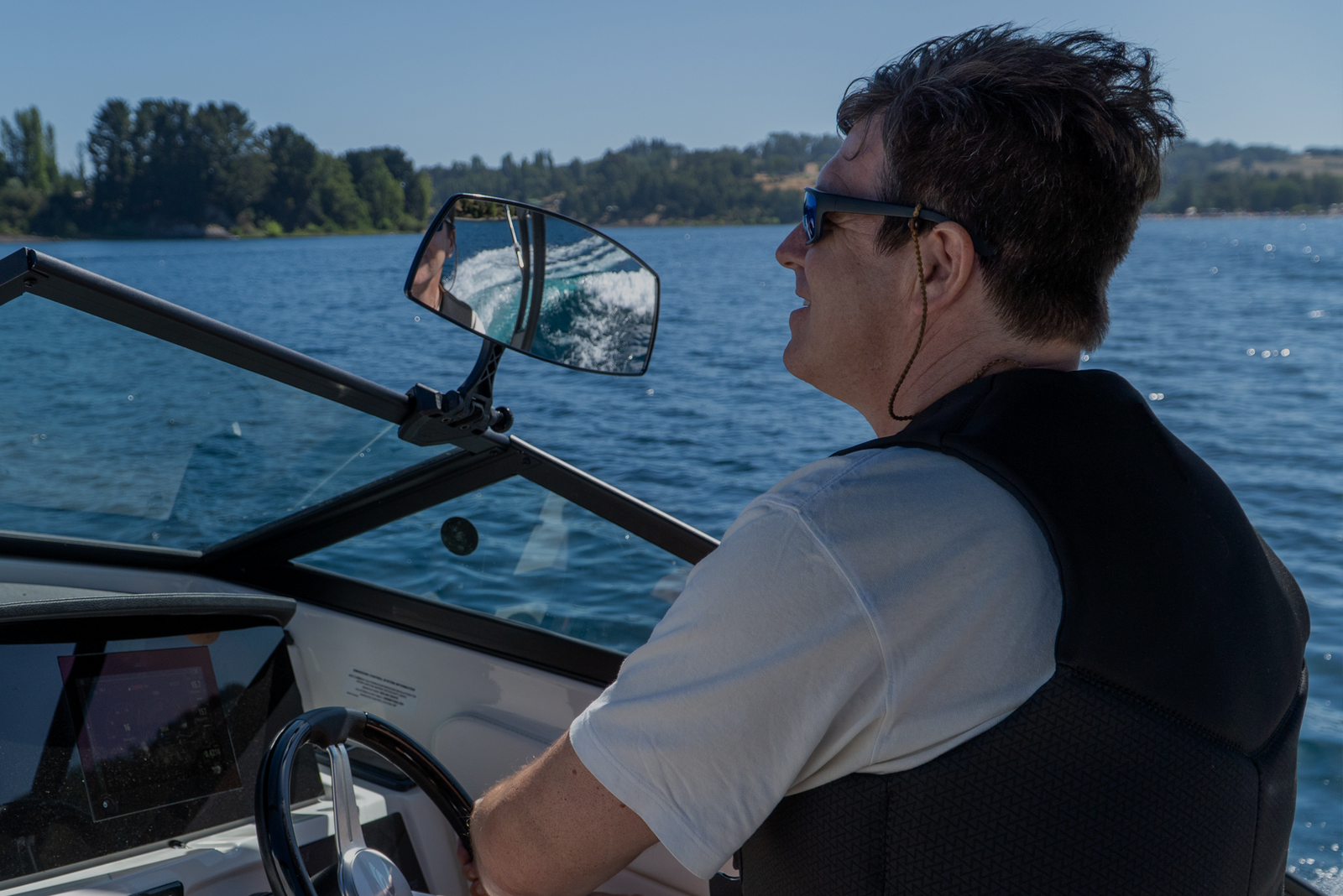 A man steering a boat with wind blowing through his hair, symbolizing freedom and choosing a captain business model.