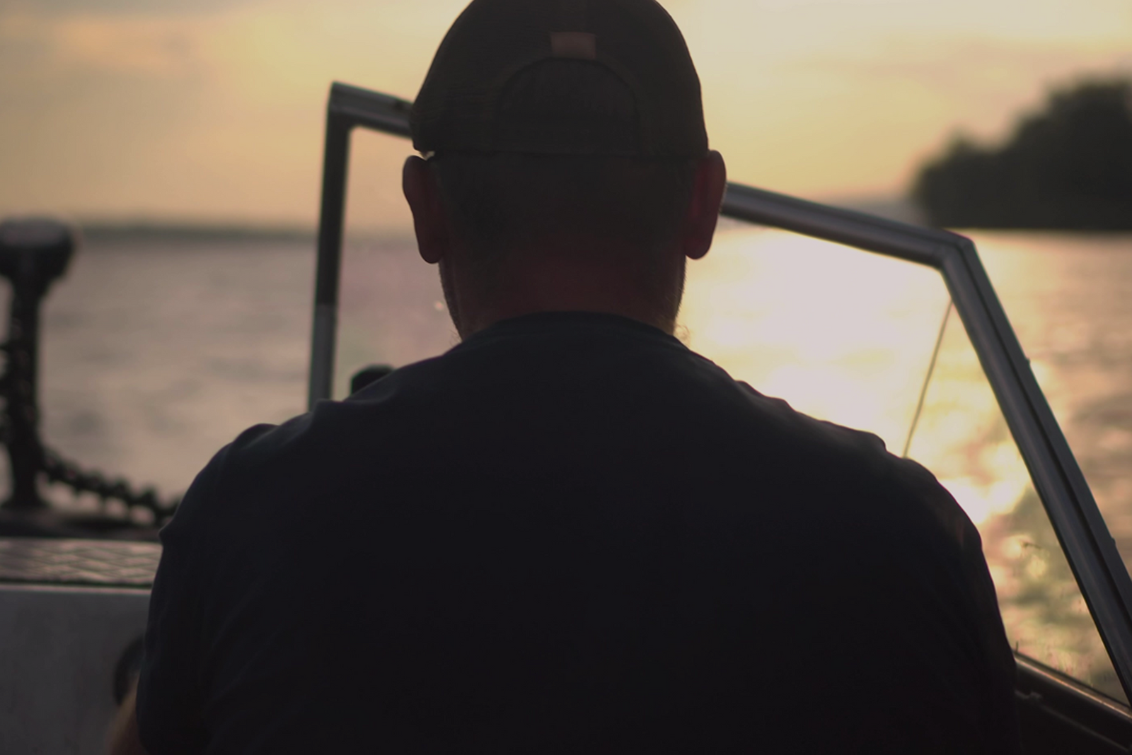Claude responded: Captain at boat helm facing golden sunset on open water, silhouetted view from behind Captain at boat helm facing golden sunset on open water, silhouetted view from behind.