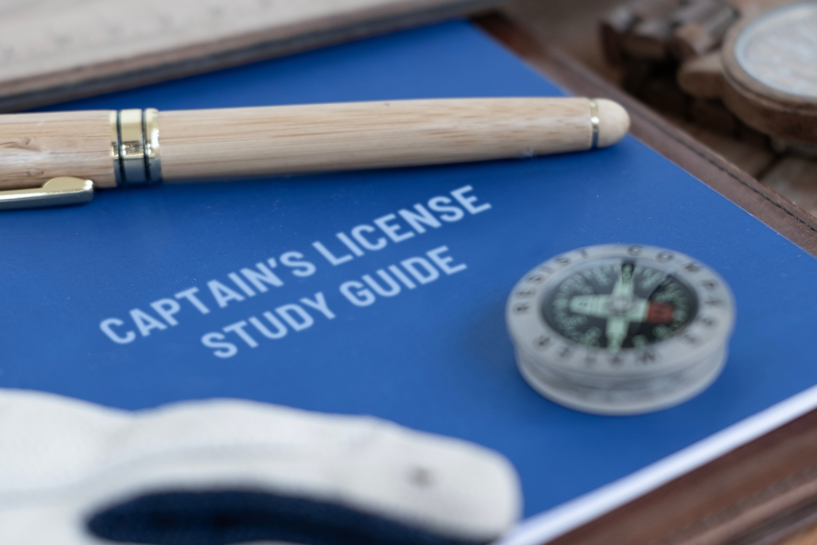 Pen resting on a blue book titled “Captain’s License Study Guide,” representing preparation for the captain’s license exam.