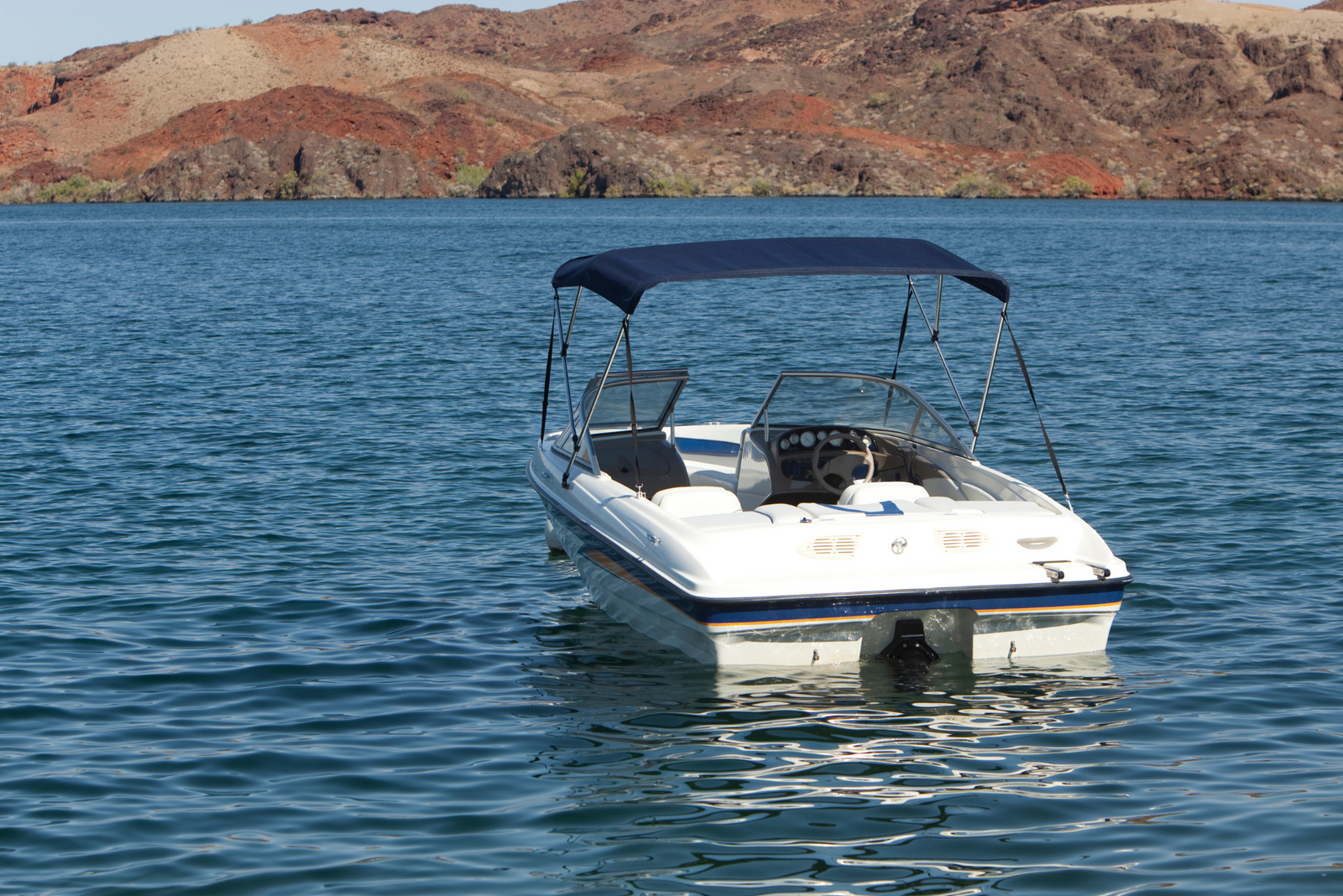A man's newly financed boat floats across calm, blue water.