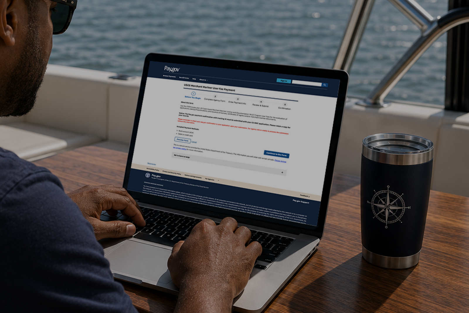 Mariner using laptop on a boat to access Pay.gov USCG fee form, representing paying MMC fees digitally.