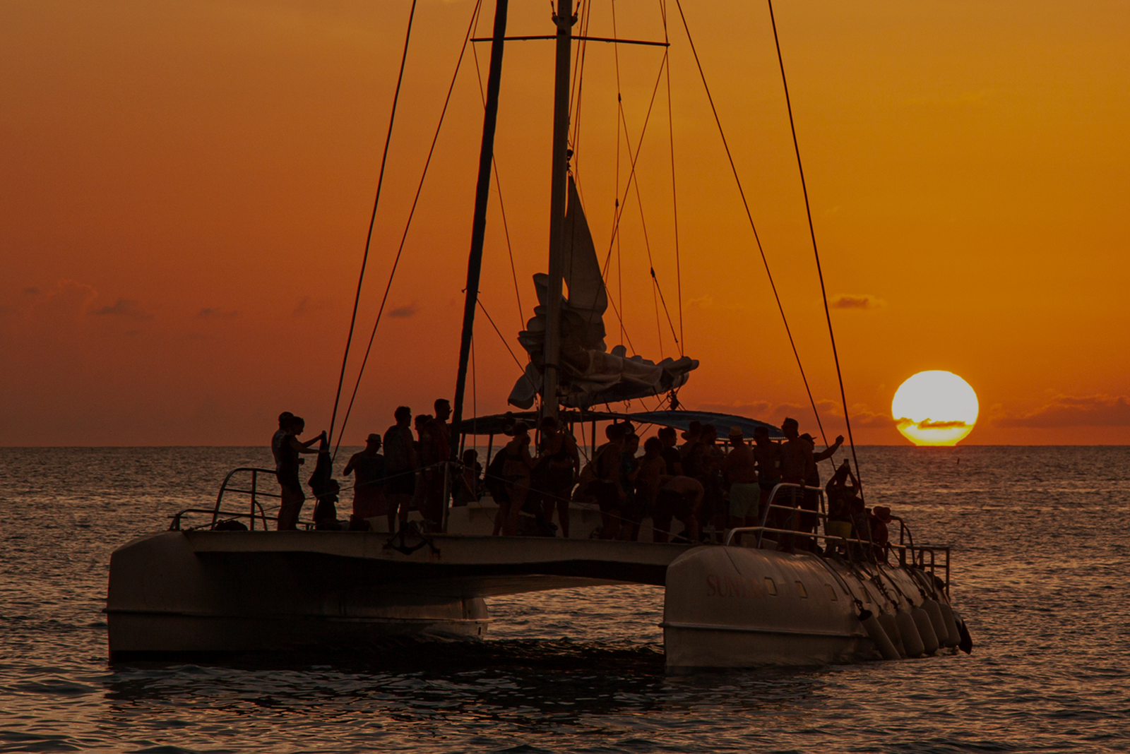 Catamaran sailing at sunset with people on deck and overlaid text about the USCG sailing endorsement.