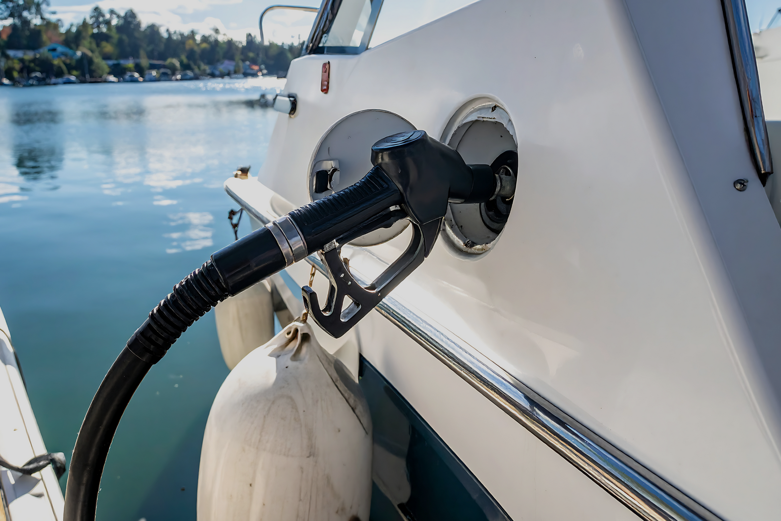 Close-up of a boat being refueled with a gas nozzle in the tank, showing fuel as a major operating cost.