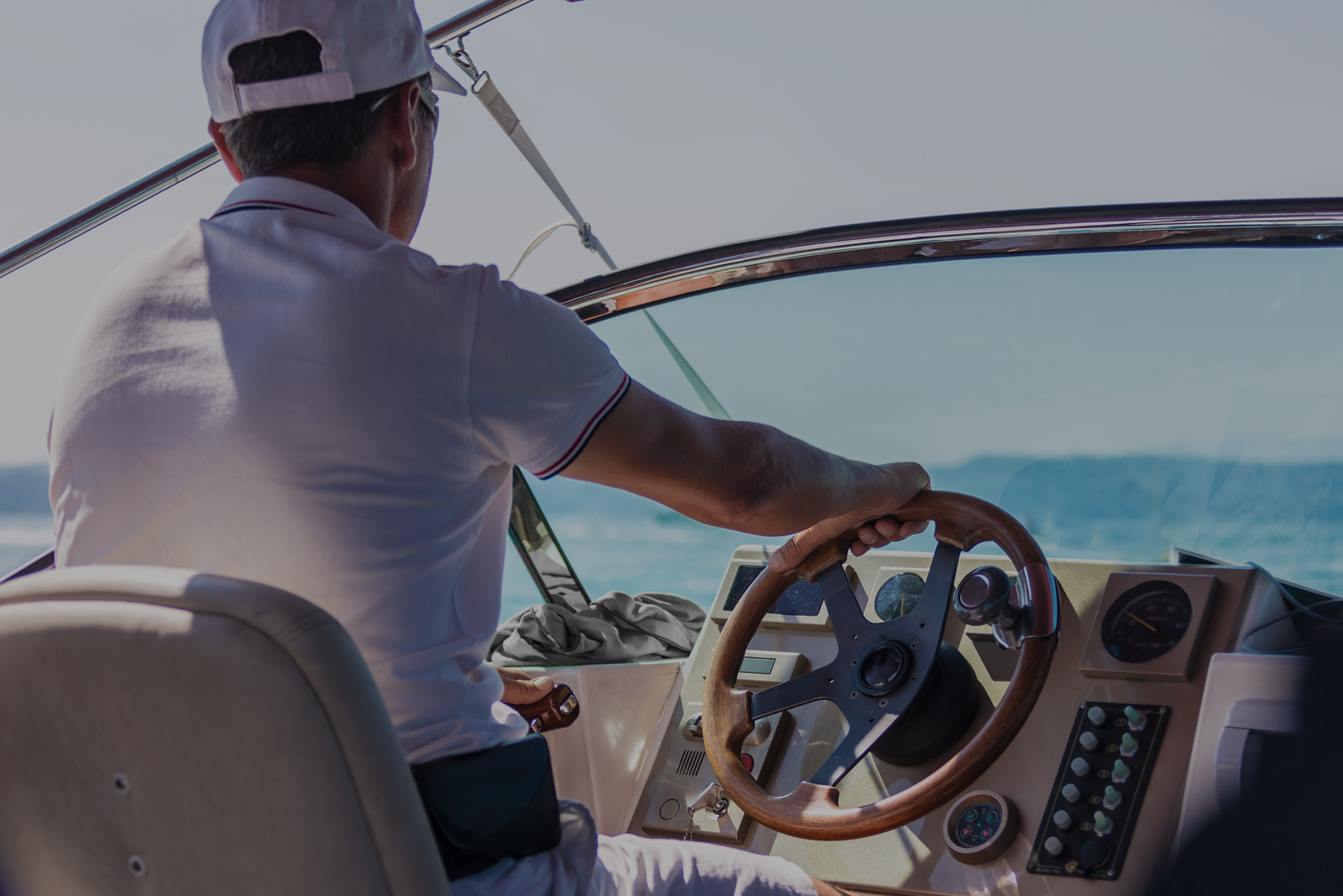Man steering a boat, emphasizing the reasons you should get a captain’s license.