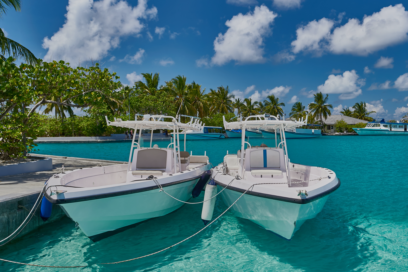 Two docked boats floating in transparent tropical water for a blog about chartering in the BVI or Bahamas.