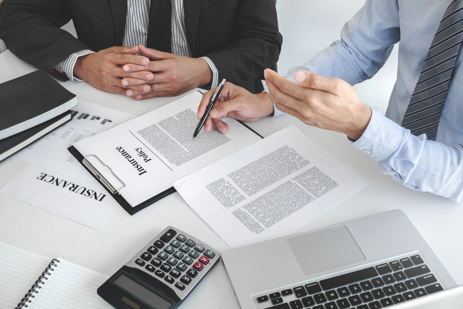 Two men in suits at a business meeting with insurance documents.