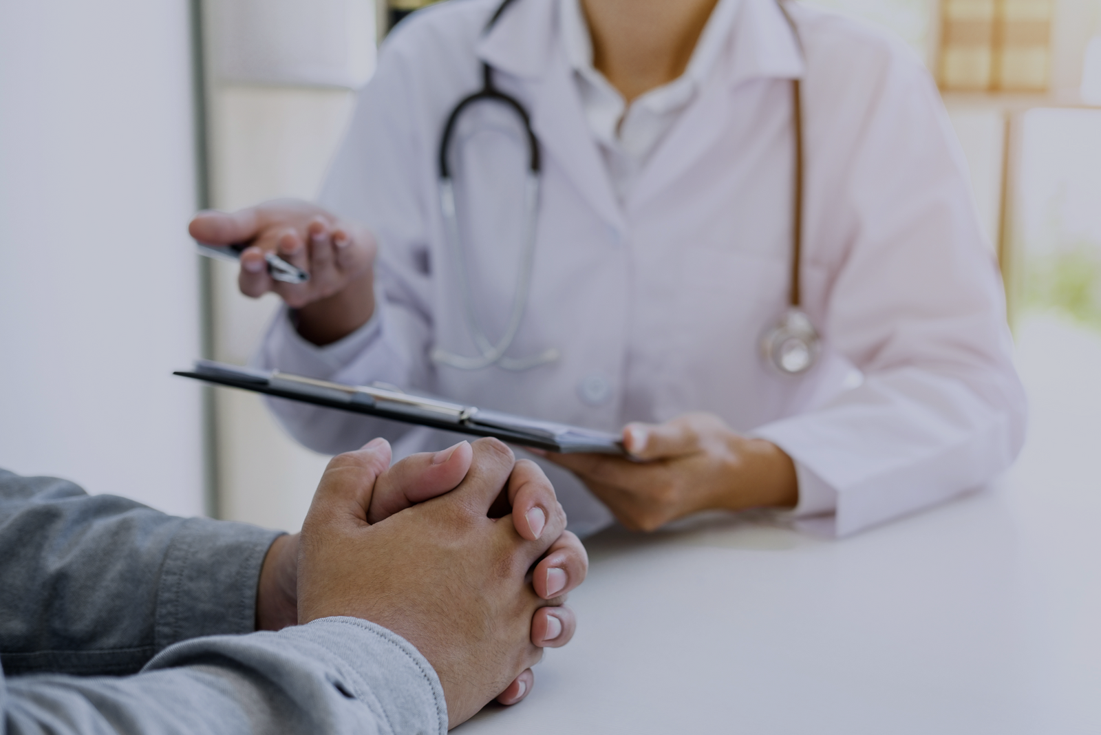 Doctor reviews clipboard with patient during medical certificate application consultation.