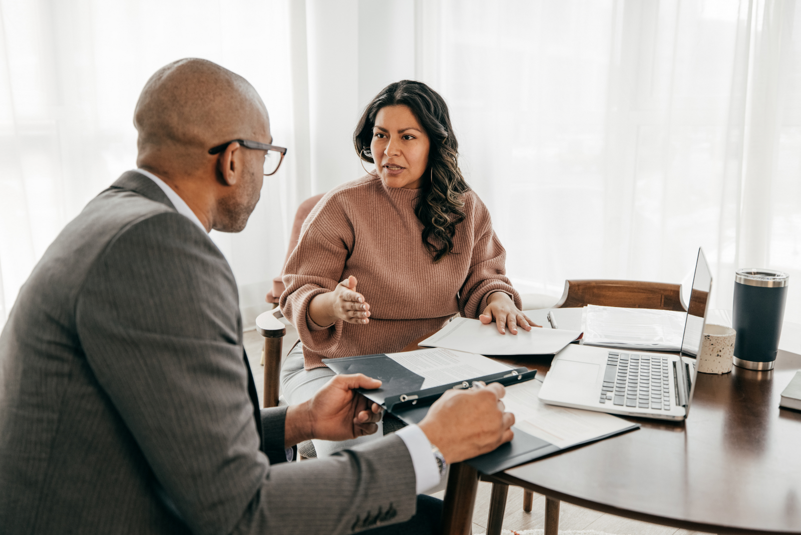 Two people engaged in a detailed discussion about needing boat insurance with paperwork present.