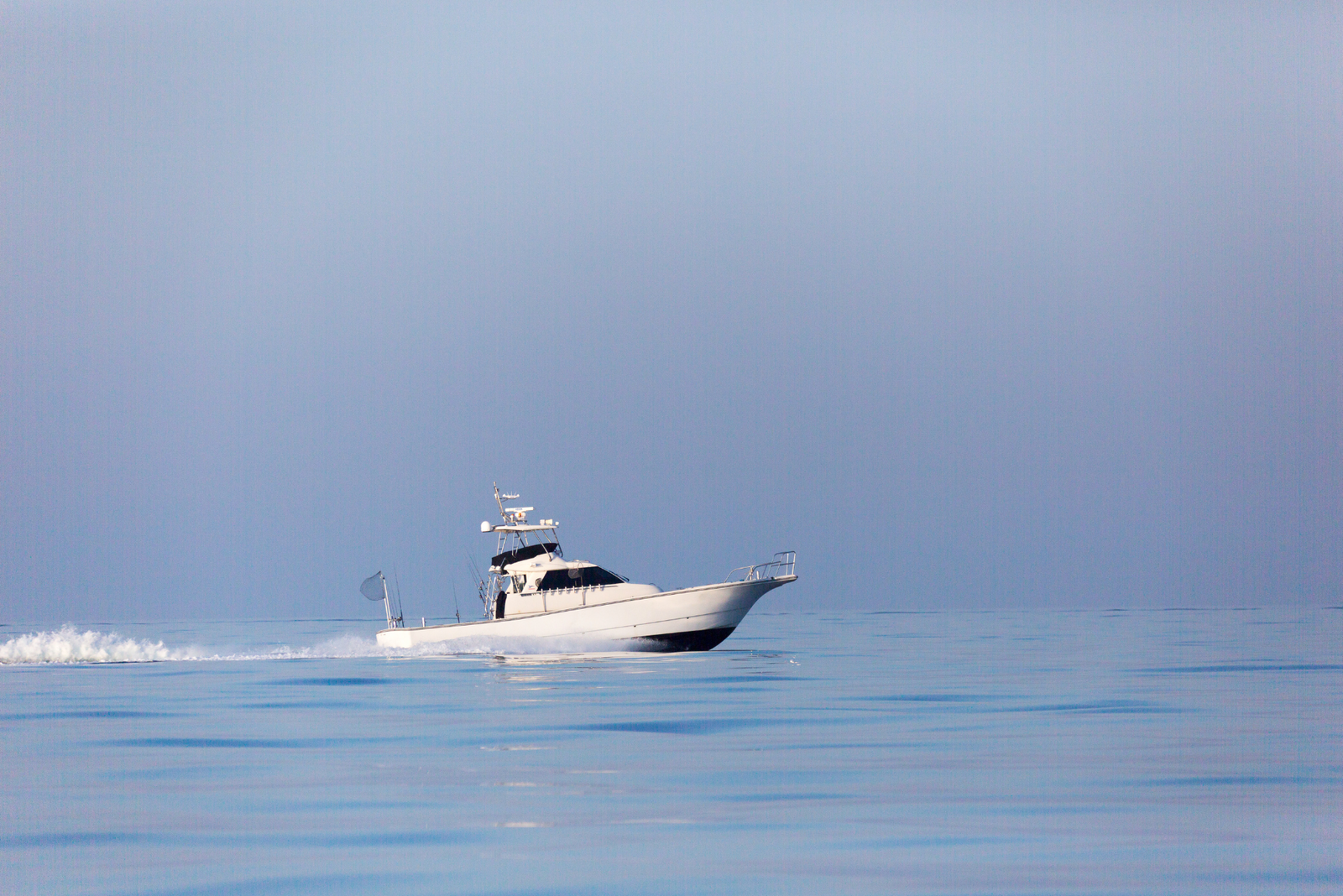 A boat motors across the water representing fines with running a charter without proper licensing.