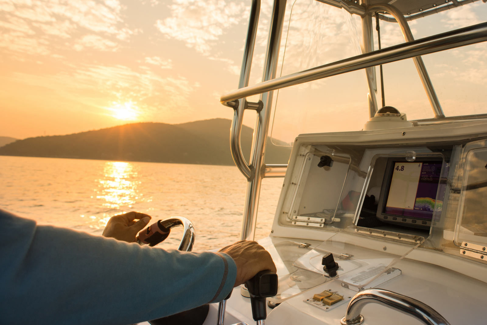 Close-up of a yacht captain steering a boat during sunset.