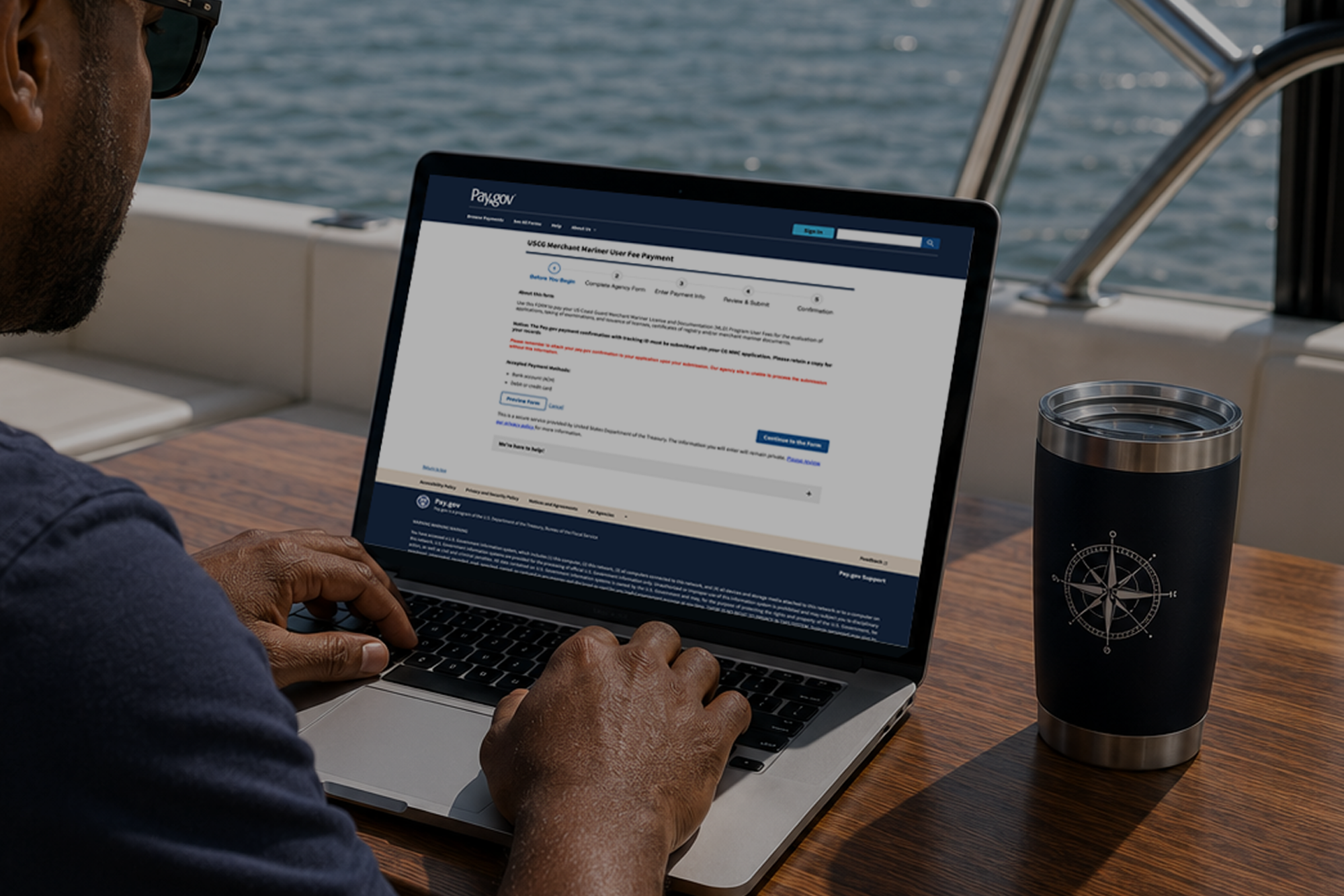 Mariner using laptop on a boat to access Pay.gov USCG fee form ...