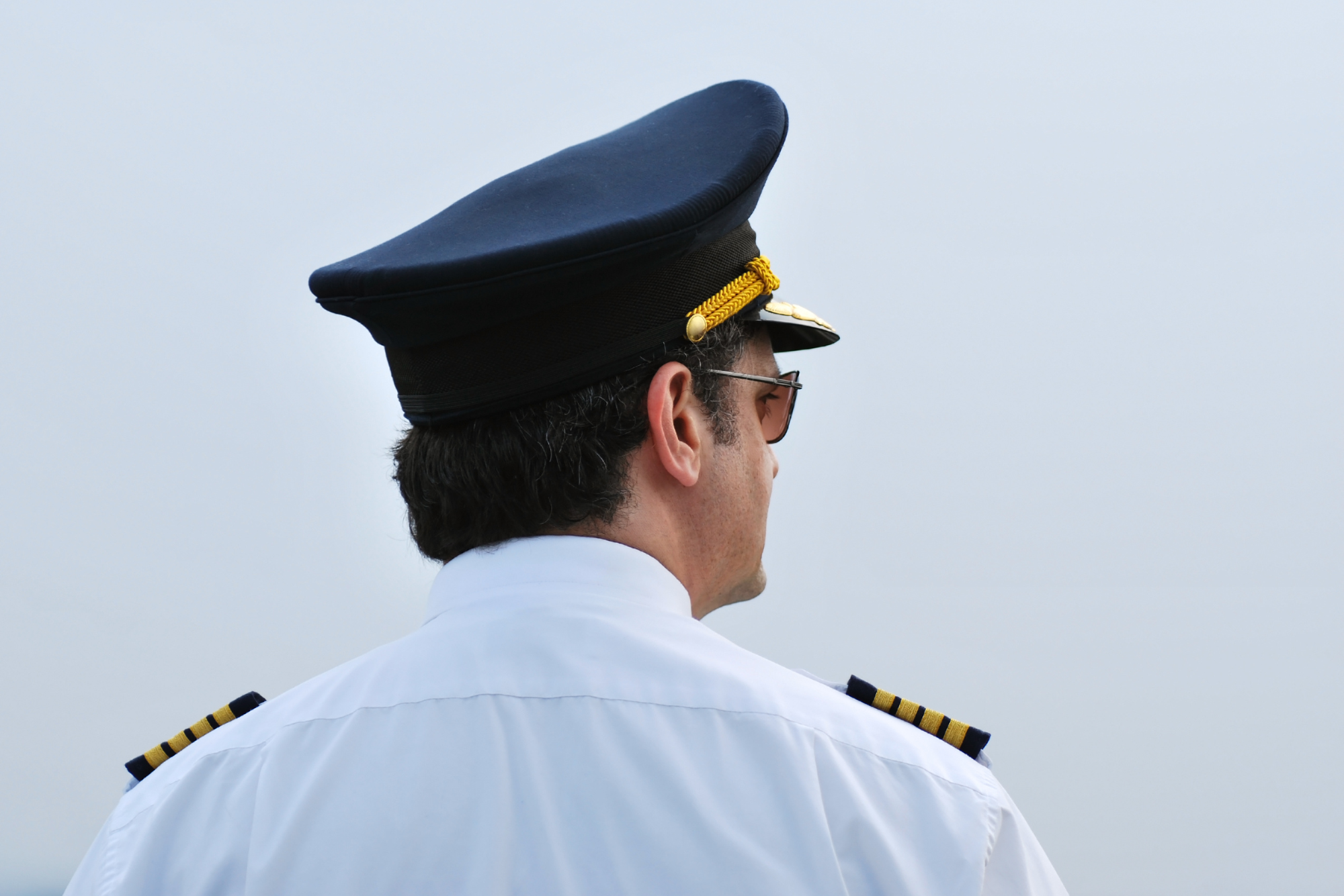 A man in a captain's hat thinks about how much his boat captain license cost.