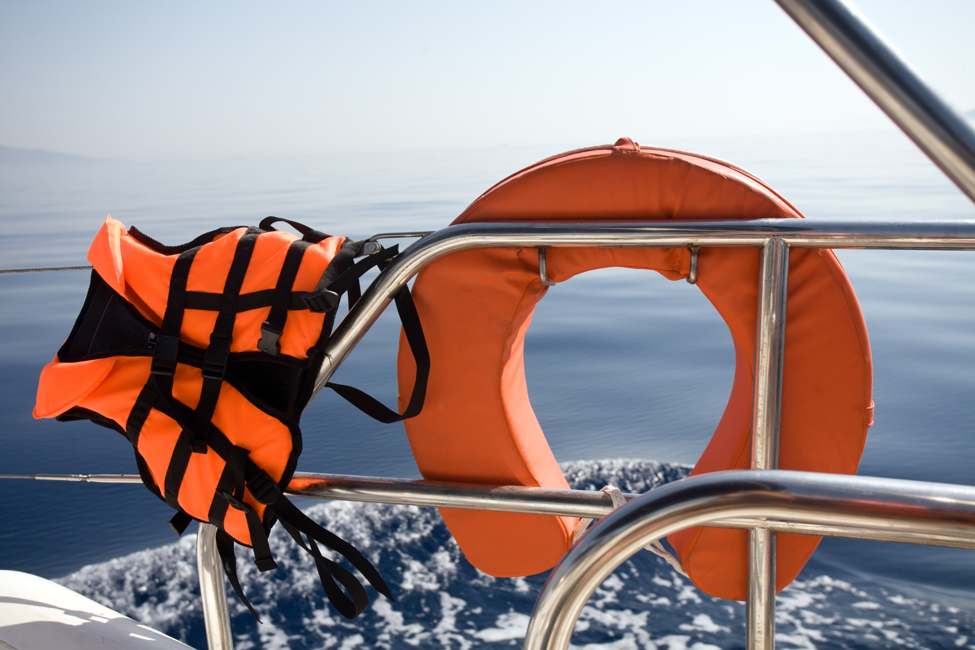 Examples of a buoyancy aid and a life jacket flap in the wind on a boat railing.