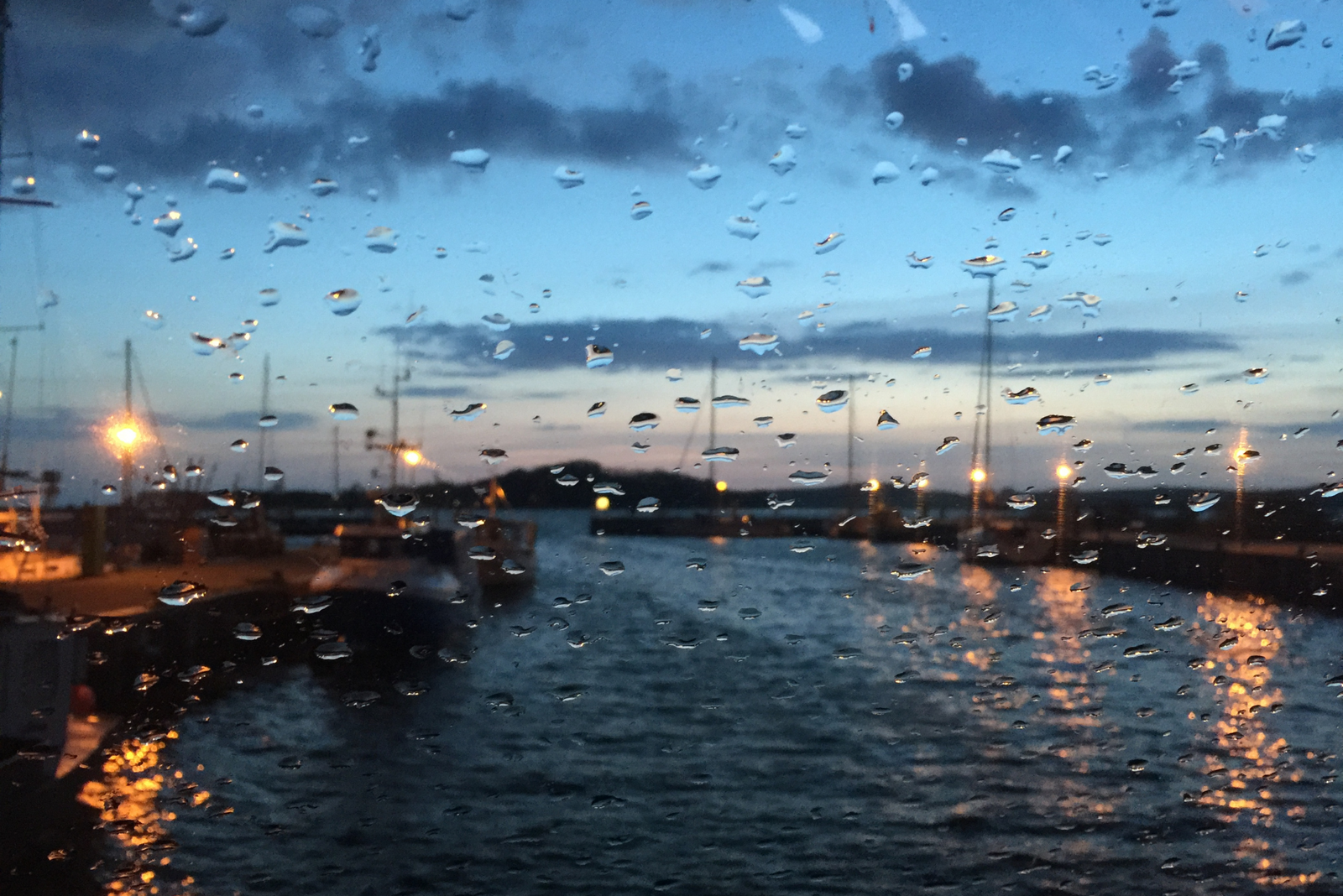 A view of a port through the windshield of a boat during bad weather.