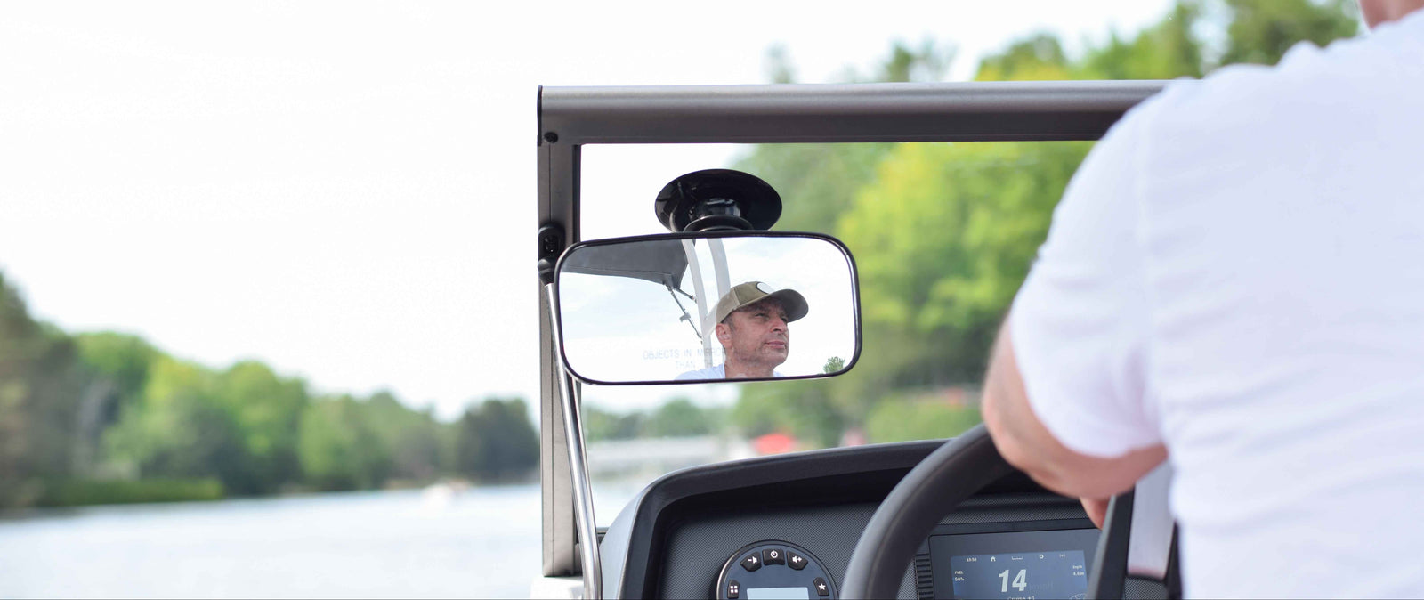 Person driving a vehicle on a waterway with trees in the background